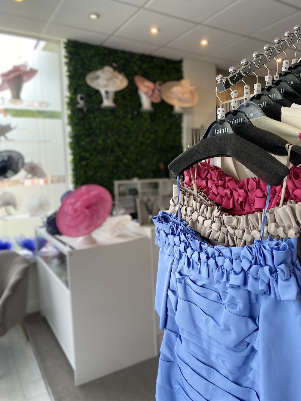 Interior of shop with Dresses on rail and hats on stands