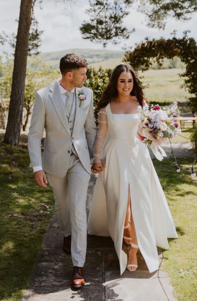 Bride and groom walking hand in hand down path