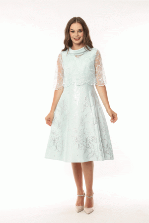 A woman in a Lizabella - 2583 light blue floral dress with sheer sleeves is smiling and standing against a white background.