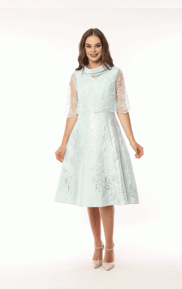 A woman in a Lizabella - 2583 light blue floral dress with sheer sleeves is smiling and standing against a white background.