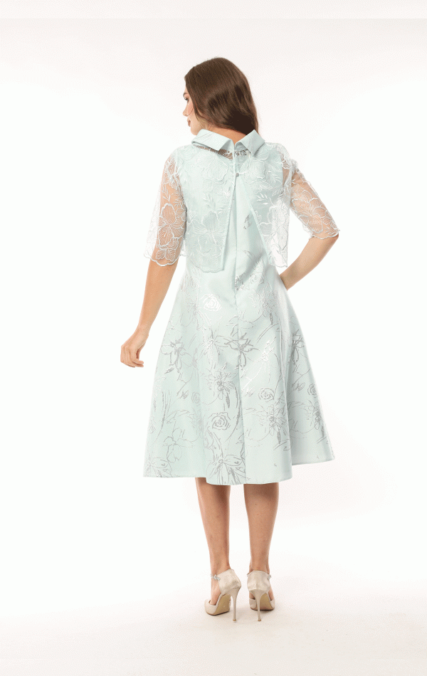 A woman in a light blue Lizabella - 2583 dress with lace sleeves and a back bow stands facing away.