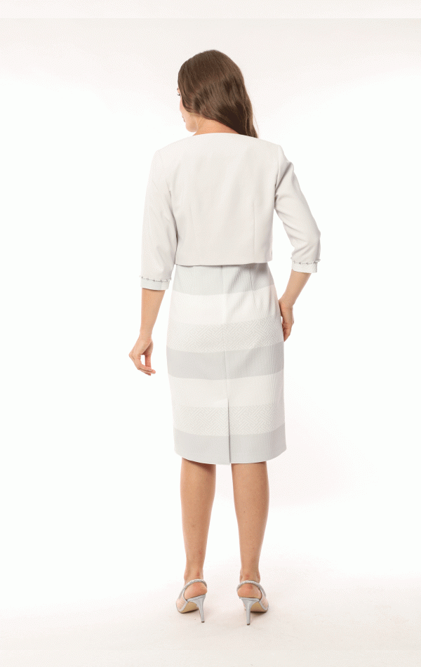 Woman in a white Lizabella 2583 dress and jacket with her back turned, standing in a white studio, wearing heels.