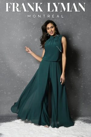 Wearing the Frank Lyman - 229127, a woman in a flowing teal outfit poses against a gray backdrop, radiating elegance and contemporary style. The name "Frank Lyman Montréal" is prominently featured above her, emphasizing the chic sophistication of the design.