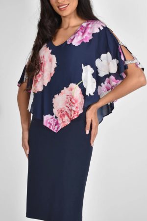 A woman exudes confidence in the Frank Lyman - 222022 creation, donning a navy knee-length dress adorned with a floral-patterned top. Smiling with one hand on her hip, she effortlessly embodies timeless fashion.