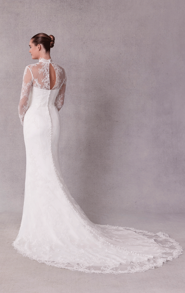 A bride gracefully stands against a gray background wearing the Mori Lee 15102 - Sibhon, an elegant white lace gown featuring a long train and back keyhole detail.