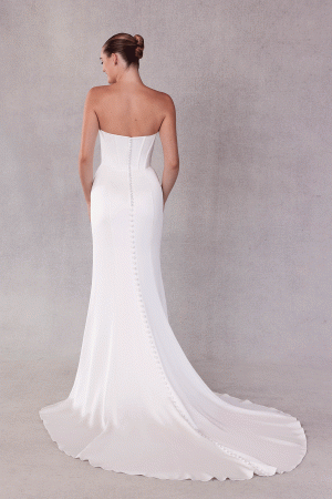 A stunning bride wears the Mori Lee 15102 - Sibhon, featuring a strapless design with a fitted bodice and luxurious long train, facing away.