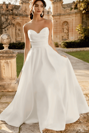 A bride in a strapless white gown poses gracefully outdoors, with the ornate architecture of the Inma (Product 44495) providing an elegant backdrop.