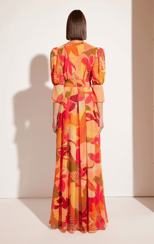 A person facing away, elegantly stands against a white background, wearing the Carla Ruiz - 51630 floral dress with puffy sleeves.