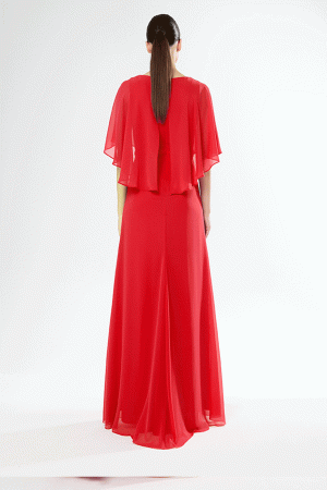 A vision in a flowing red gown with a cape-like top, reminiscent of Carla Ruiz's 51633 design, stands gracefully against a white background.