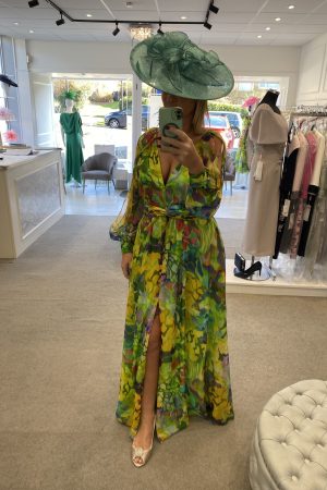 Amidst the elegant clothing racks, a vibrant scene unfolds as a person captures a selfie while wearing a Carla Ruiz - 51662 floral dress and wide-brim hat.