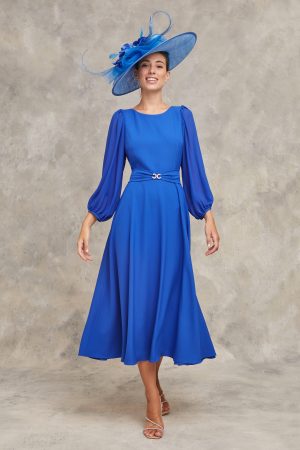 Evoking classic beauty, the woman wears the Claudia C - Renoir bright blue midi dress with a matching feathered wide-brimmed hat against a neutral background.