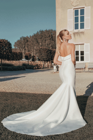 The bride, in a stunning Justin Alexander 44456 - Paris strapless white gown with a long train, stands outside a villa gazing towards Paris.