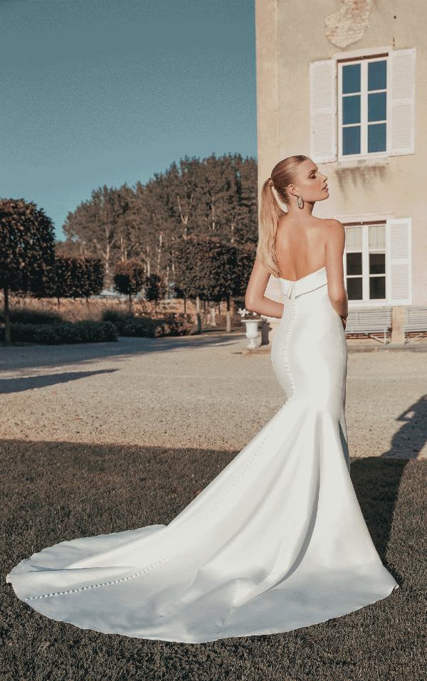 The bride, in a stunning Justin Alexander 44456 - Paris strapless white gown with a long train, stands outside a villa gazing towards Paris.