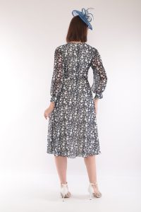 Woman in a blue polka dot Lizabella - 2649 dress with a matching blue fascinator, standing with her back to the camera.