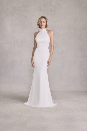 Woman in the Morilee 15101 - Sandi sleeveless, high-neck, floor-length white dress stands against a plain light gray background.