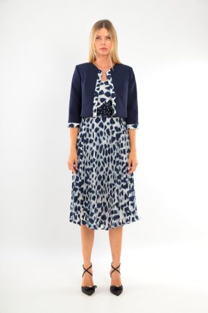 Woman in a blue and white animal print dress with a navy cropped jacket and black heels, standing straight.