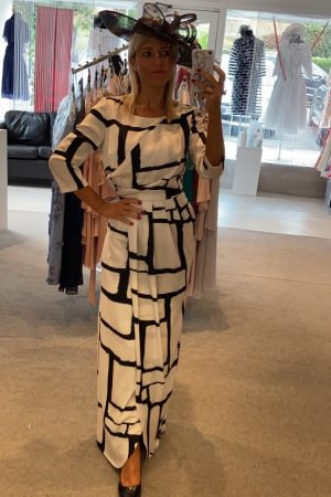 Woman in a Carla Ruiz - 96560 black and white geometric print dress and wide-brimmed hat takes a mirror selfie in a boutique.