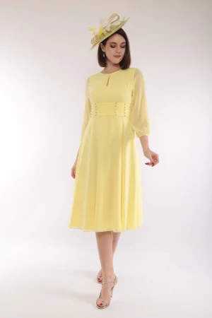 A woman wears the Lizabella - 2662 pale yellow midi dress with a matching hat, posing against a plain white background.