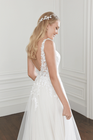 Woman wearing Sincerity Willow Ivory lace wedding dress, size 10, with low back and floral hair accessory indoors. £695.