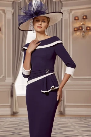 A woman in a Veni Infantino - 992001AB navy and white dress with a wide-brimmed hat stands in an elegant room.