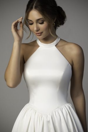SY8273 - Anaïs wedding dress by Stella York has a high-neck line which is perfectly worn with an elegant updo by a bride to be who is looking down as she gently touches her hair.