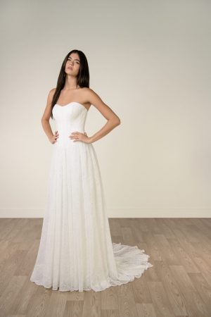 A modern bride wears the Stella York SY8341 - strapless all over lace wedding dress, standing on a barn style wedding wooden floor against a plain whitewash wall.